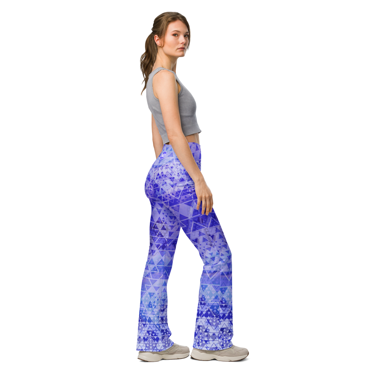 Woman wearing high-waisted flare leggings in a white, blue, and purple gradient inspired by sacred geometry, featuring a butt-lifting cut, soft compression fabric, and a double-layered waistband — designed for comfort, style, and spiritual expression.
