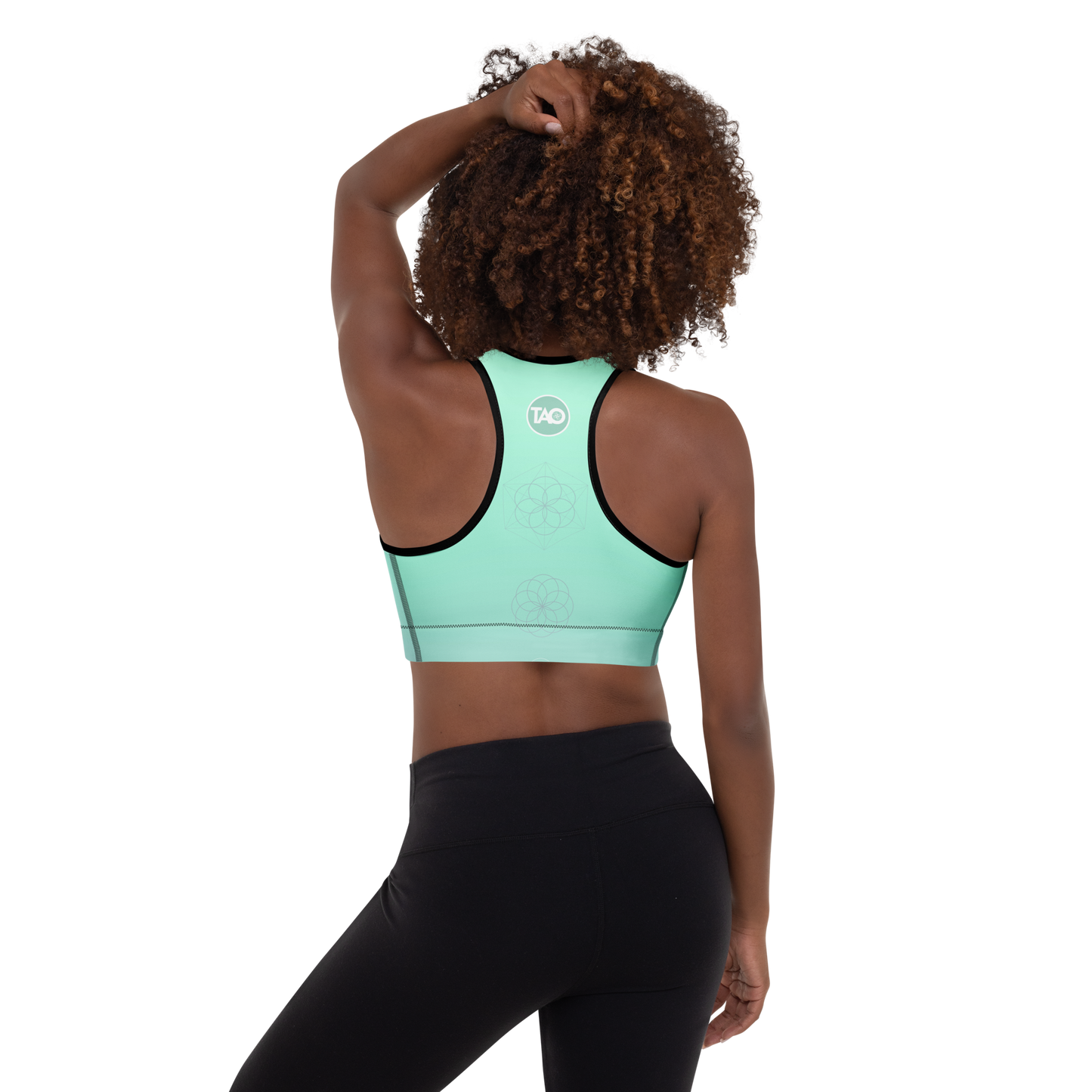 Woman wearing a mint green sports bra with sacred mandala print, scoop neckline, racerback design, and wide underband — made for flexible movement and calm, conscious strength.