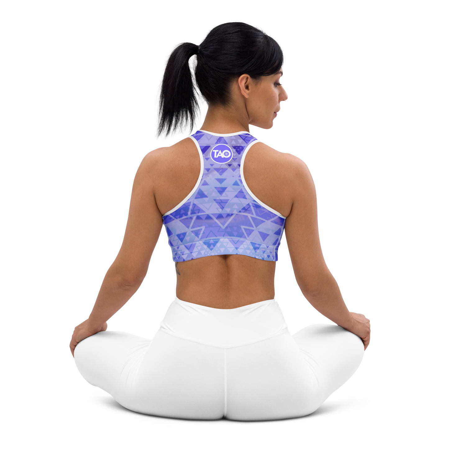 Woman wearing a blue and white sacred geometry sports bra with a scoop neckline, racerback design, and wide elastic underband — crafted for support, flexibility, and mindful movement in a spiritually inspired design.