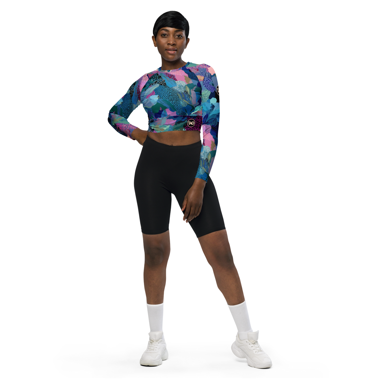 Woman wearing a blue camo-print long sleeve crop top with raglan sleeves, double-layered waistband, and UPF 50+ protection — made from recycled fabric for stylish, eco-conscious performance.