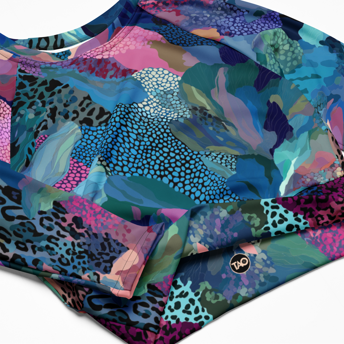 a blue camo-print long sleeve crop top with raglan sleeves, double-layered waistband, and UPF 50+ protection — made from recycled fabric for stylish, eco-conscious performance.