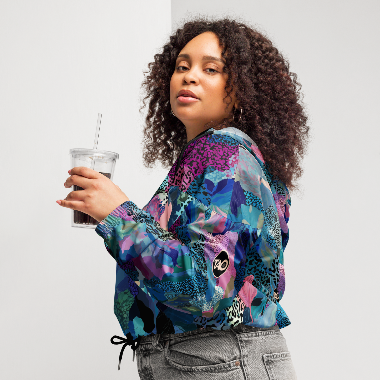Cropped windbreaker featuring a bold blue camo print with adjustable hood and waist drawcords, breathable mesh lining, and side-slit pockets — designed for lightweight protection and standout style.