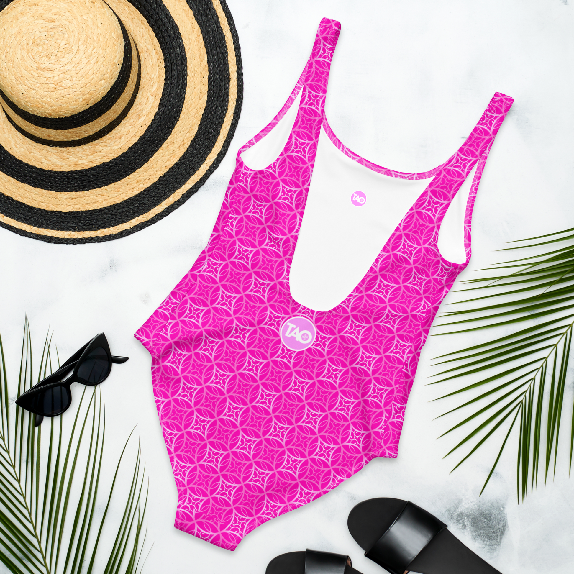 Woman wearing a pink one-piece swimsuit with scoop neckline, low scoop back, and cheeky fit — made from chlorine-resistant, four-way stretch fabric with sacred geometry-inspired design.