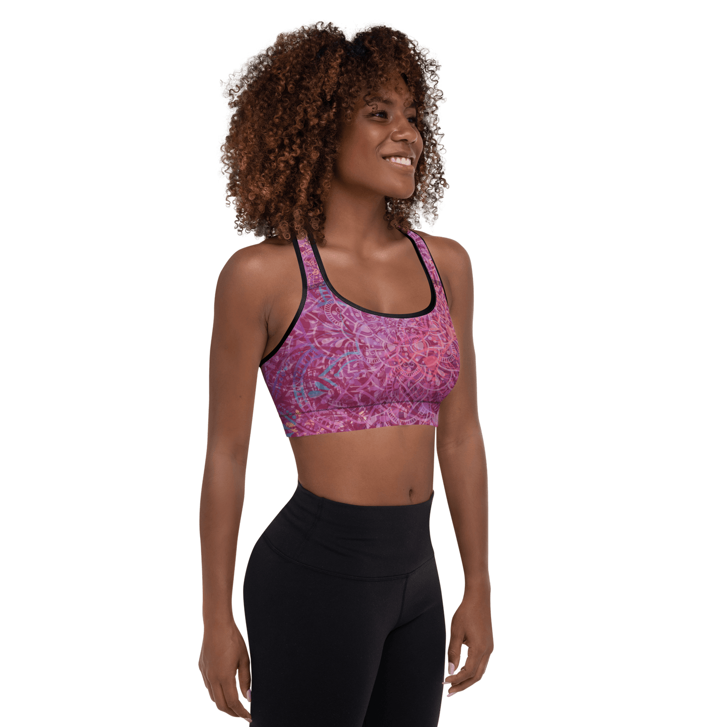 Woman in a vibrant Mandala Glow sports bra, mid-stretch in a serene outdoor yoga setting, showcasing comfort and style.