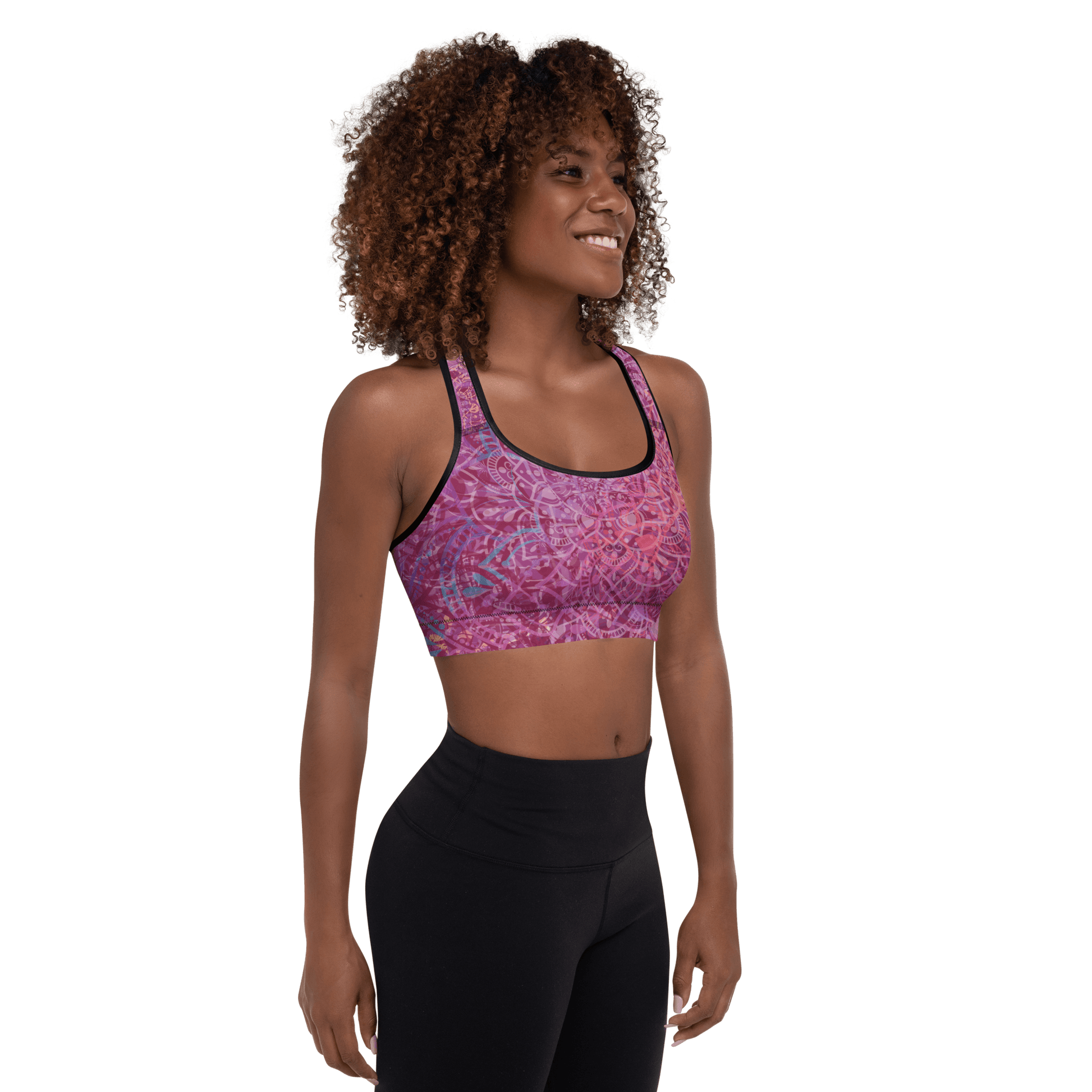 Woman in a vibrant Mandala Glow sports bra, mid-stretch in a serene outdoor yoga setting, showcasing comfort and style.
