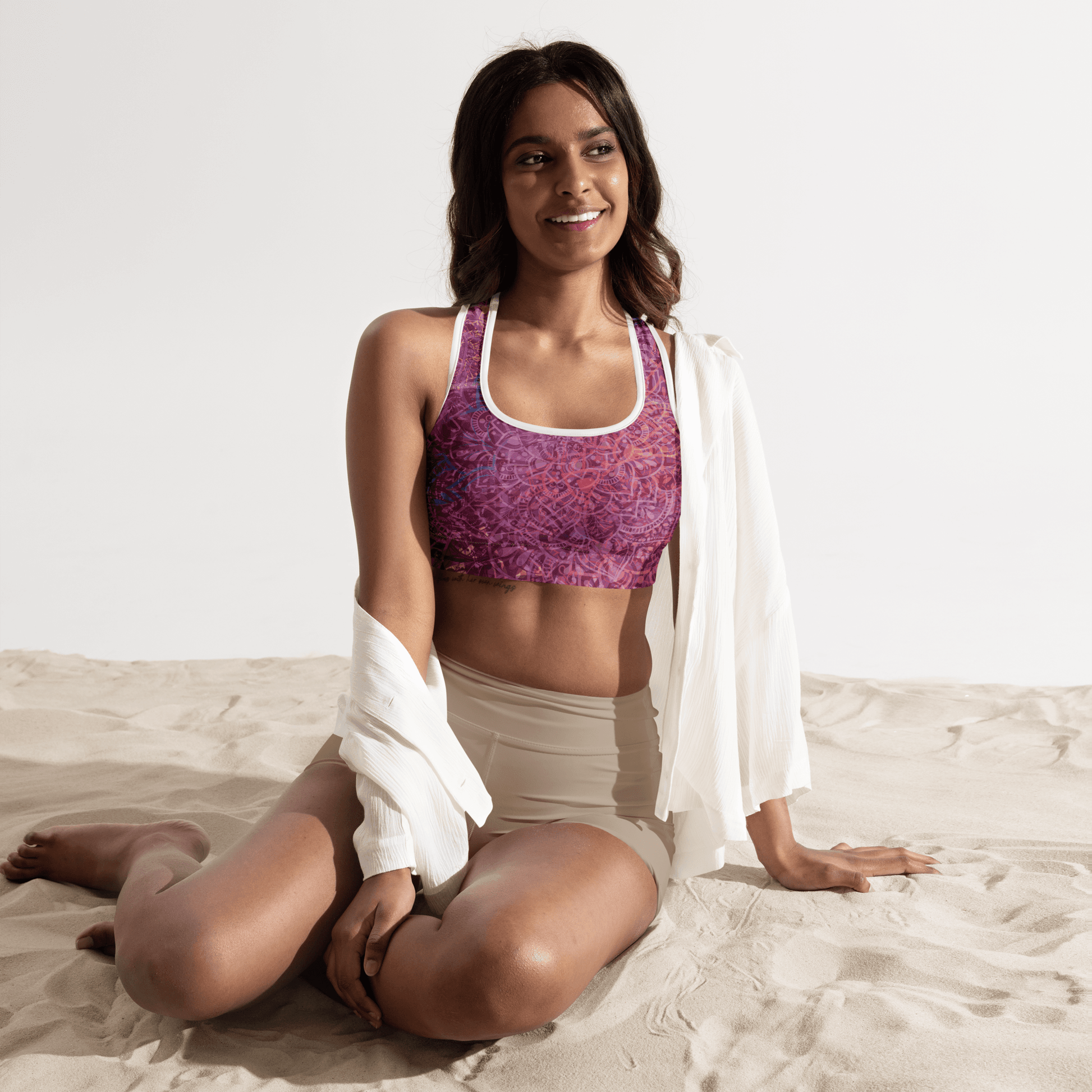 Woman in a vibrant Mandala Glow sports bra, mid-stretch in a serene outdoor yoga setting, showcasing comfort and style.