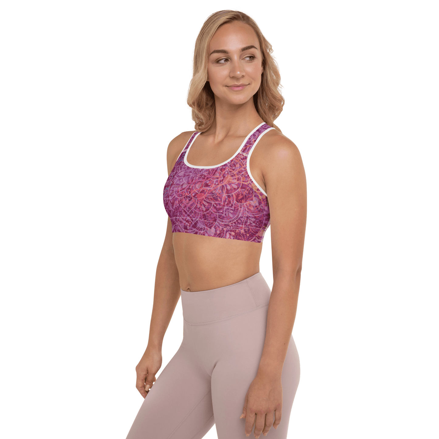 Woman in a vibrant Mandala Glow sports bra, mid-stretch in a serene outdoor yoga setting, showcasing comfort and style.
