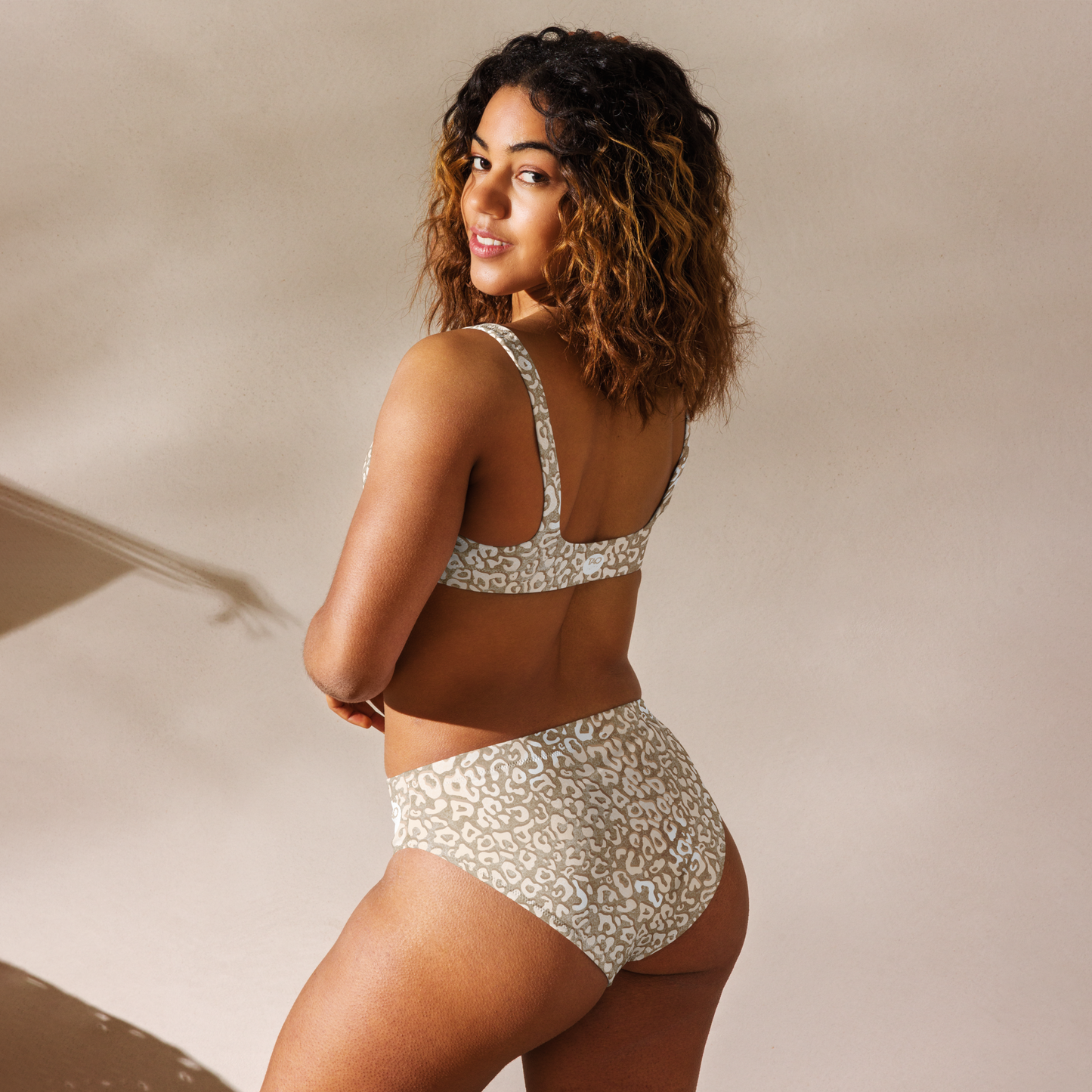 Woman wearing a leopard-print sports bikini with a supportive sporty cut, removable padding, and double-layered fabric made from recycled material — perfect for active swimwear with fierce, conscious style.