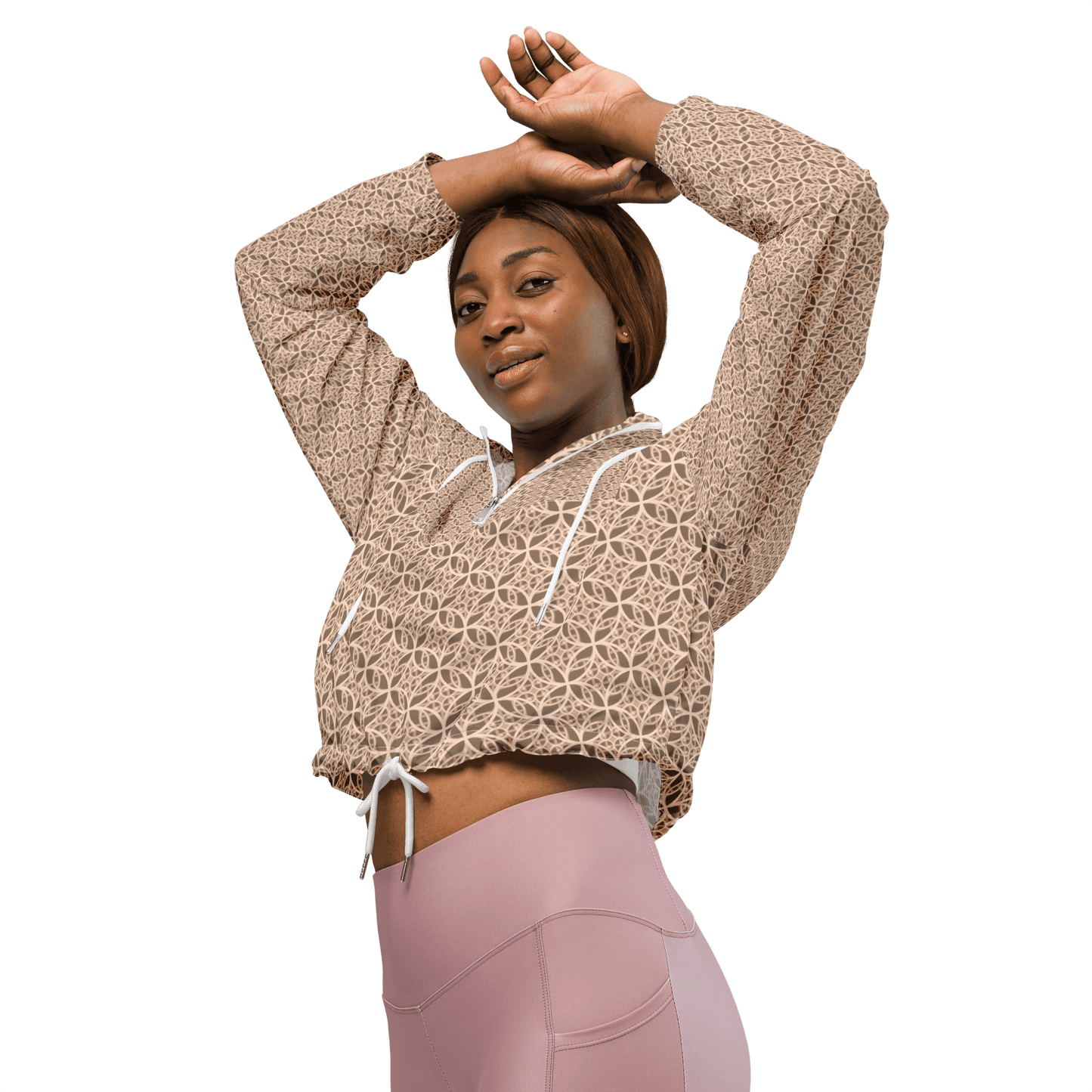Woman wearing a lightweight beige cropped windbreaker with monogram Fibonacci pattern, featuring adjustable drawcords, side-slit pockets, and mesh lining — a waterproof, sacred-geometry inspired layer for mindful movement and conscious living.